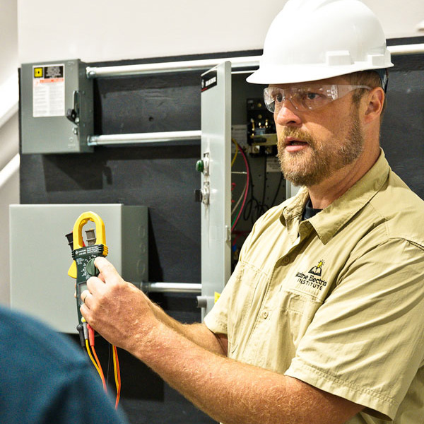 Instructor demonstrating electrical testing with safety gear.